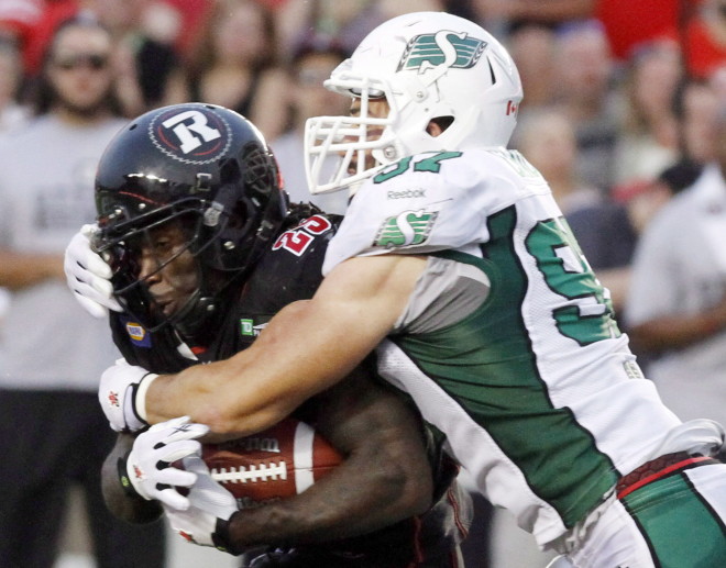 Saskatchewan Roughriders' John Chick(97) trackles Ottawa Red Blacks' Chevon Walker (29) during CFL football action in Ottawa, Saturday August 2, 2014. THE CANADIAN PRESS/Fred Chartrand