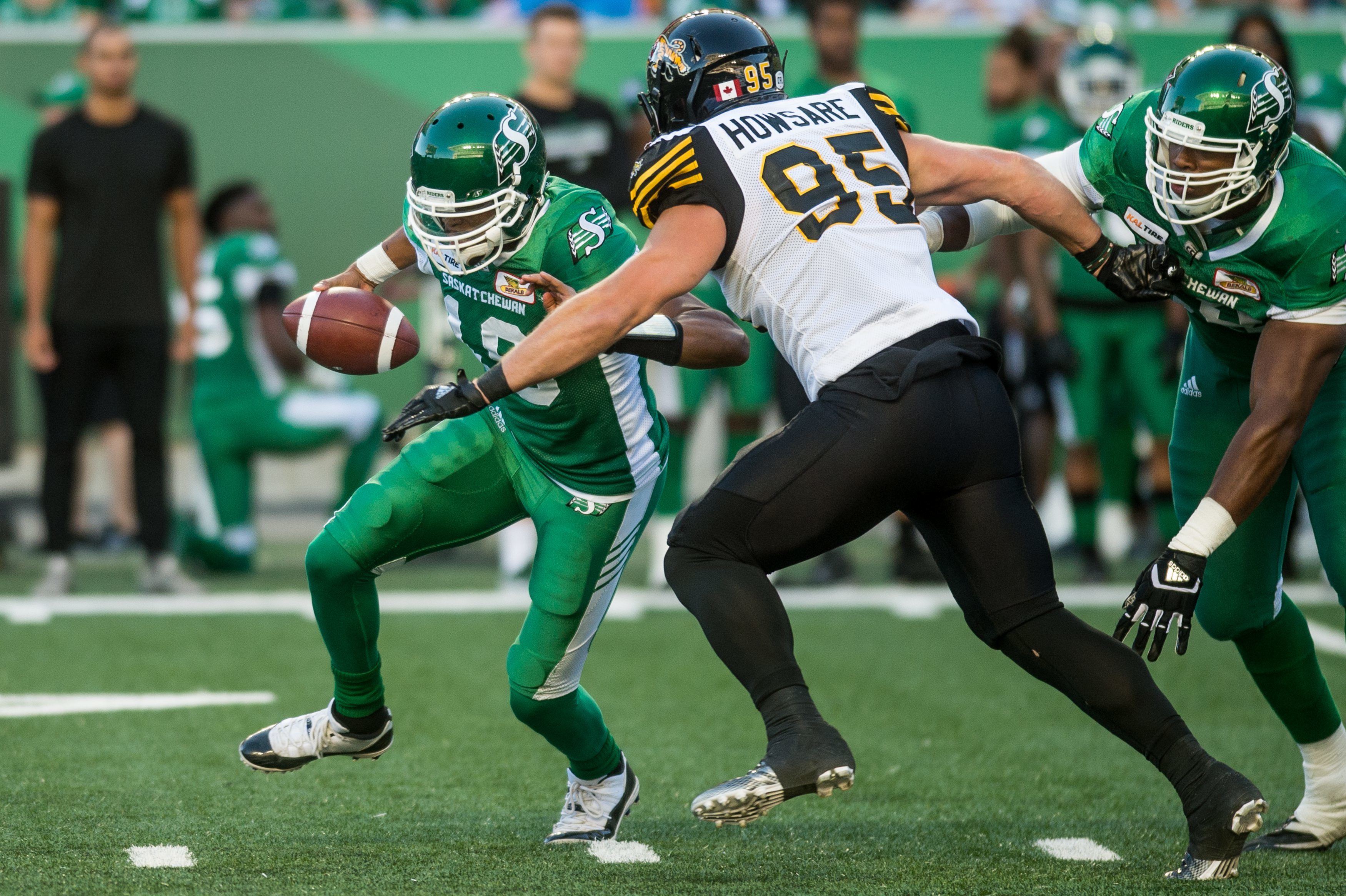 Saskatchewan Roughriders quarterback Brandon Bridge (16) runs the ball under pressure from Hamilton Tiger-Cats defensive end Julian Howsare (95) during first half CFL action in Regina on Thursday, July 5, 2018. (CFL PHOTO - MATT SMITH)